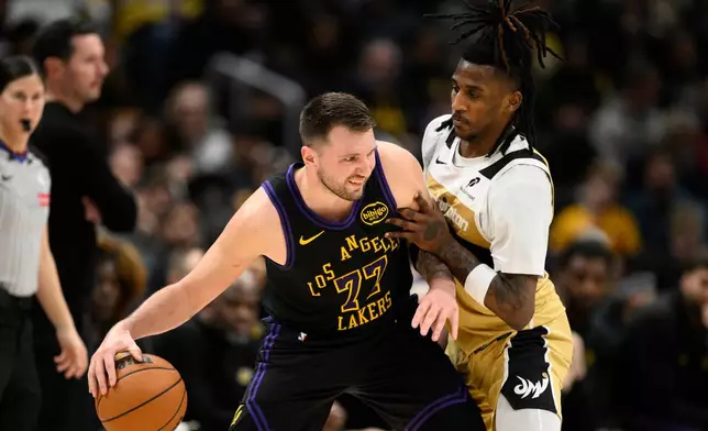 Los Angeles Lakers guard Luka Doncic (77) dribbles against Washington Wizards guard Jamir Watkins, right, during the first half of an NBA basketball game, Friday, Jan. 30, 2026, in Washington. (AP Photo/Nick Wass)