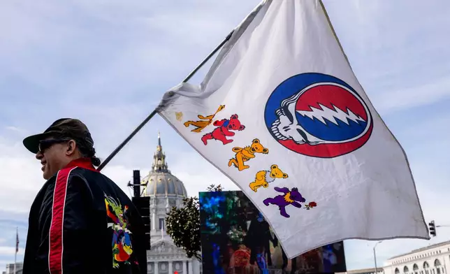 An attendee waves a flag during a public memorial for Grateful Dead co-founder Bob Weir at Civic Center Plaza in San Francisco, Saturday, Jan. 17, 2026. (Stephen Lam/San Francisco Chronicle via AP)