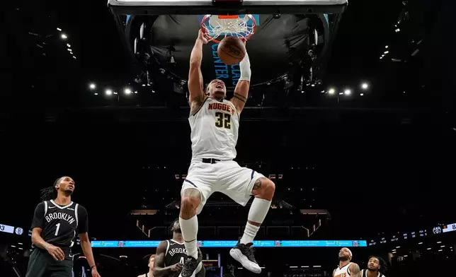Denver Nuggets forward Aaron Gordon (32) hangs from the rim after dunking during the second half of an NBA basketball game against the Brooklyn Nets, Sunday, Jan. 4, 2026, in New York. (AP Photo/Yuki Iwamura)