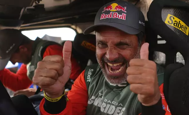 Driver Nasser Al-Attiyah of Qatar, right, and co-driver Fabian Lurquin of Belgium celebrate winning the Dakar Rally after the thirteenth stage with a start and finish in Yanbu, Saudi Arabia, Saturday, Jan.17, 2026. (AP Photo/Thibault Camus)