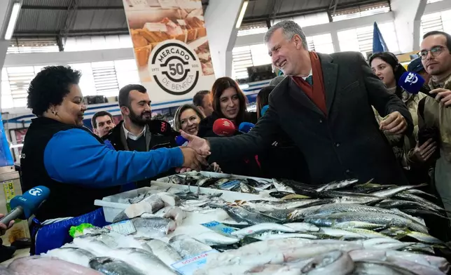 Presidential candidate Henrique Gouveia e Melo, a retired Rear Admiral running as an independent, shakes hands with a fish seller at a market in Lisbon, Friday, Jan. 16, 2026, while campaigning for Sunday's presidential election. (AP Photo/Armando Franca)
