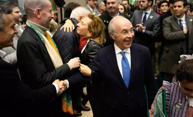 Presidential candidate Luis Marques Mendes, center right, from the center-right Social Democratic Party, with his wife Rosa Sofia Salazar, in the background, greets supporters while campaigning for Sunday's presidential election, in Lisbon, Portugal, Friday, Jan. 16, 2026. (AP Photo/Armando Franca)