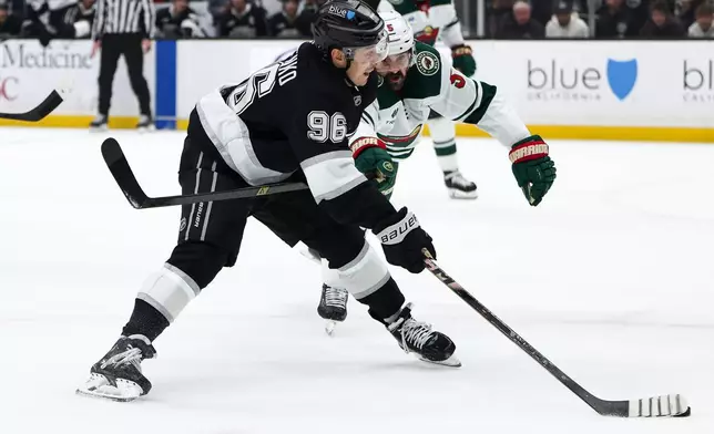 Los Angeles Kings left wing Andrei Kuzmenko (96) passes the puck as Minnesota Wild defenseman Jake Middleton, right, defends during the second period of an NHL hockey game, Monday, Jan. 5, 2026, in Los Angeles. (AP Photo/Jessie Alcheh)
