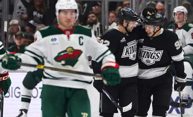 Los Angeles Kings left wing Kevin Fiala, center, and Los Angeles Kings left wing Andrei Kuzmenko (96) celebrate after a goal as Minnesota Wild defenseman Jared Spurgeon, left, skates during the second period of an NHL hockey game, Monday, Jan. 5, 2026, in Los Angeles. (AP Photo/Jessie Alcheh)