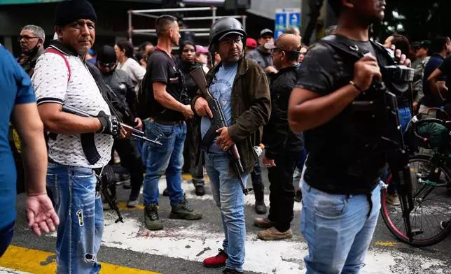 Pro-government armed civilians attend a protest demanding the release of President Nicolas Maduro and first lady Cilia Flores, the day after U.S. forces captured and flew them to the United States, in Caracas, Venezuela, Sunday, Jan. 4, 2026. (AP Photo/Ariana Cubillos)