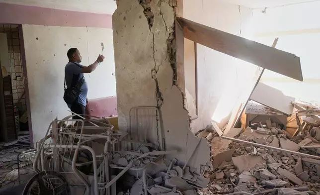 Reggie Carrera looks at the damage at the home of his friend Jesus Linares, who says it was hit during U.S. military operations to capture Venezuelan President Nicolas Maduro, in Catia La Mar, Venezuela, Sunday, Jan. 4, 2026. (AP Photo/Matias Delacroix)