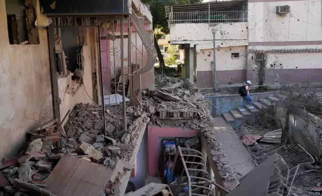 A neighbor walks through an apartment building that residents say was damaged during U.S. military operations to capture Venezuelan President Nicolás Maduro, in Catia La Mar, Venezuela, Sunday, Jan. 4, 2026. (AP Photo/Matias Delacroix)