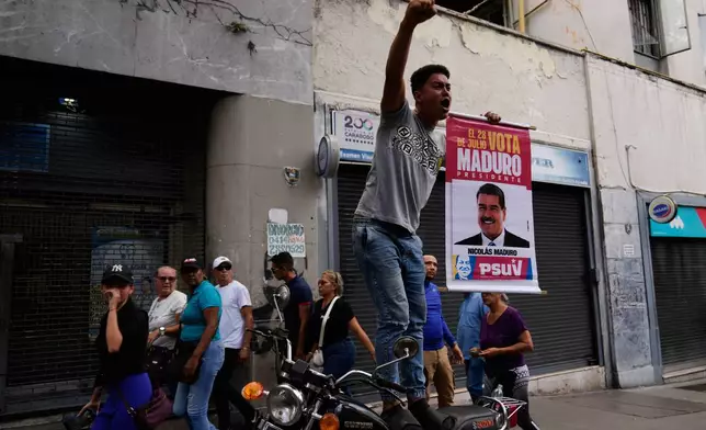 A government supporter holds a banner for President Nicolas Maduro during a protest demanding his release, after U.S. forces captured and flew him to the United States, in Caracas, Venezuela, Sunday, Jan. 4, 2026. (AP Photo/Ariana Cubillos)
