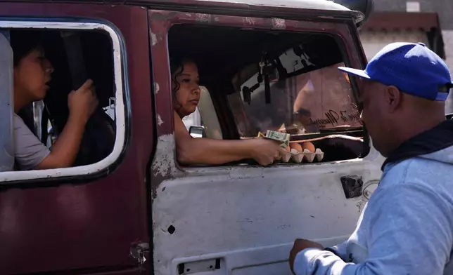 A woman buys eggs at a market in Caracas, Venezuela, Sunday, Jan. 4, 2026. (AP Photo/Ariana Cubillos)