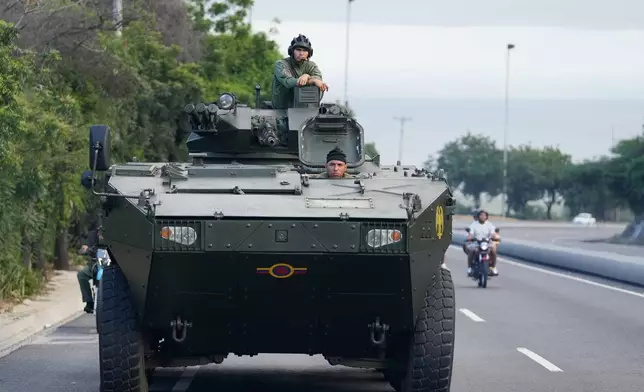 A soldier stands atop an armored vehicle on the highway leading from the international airport toward Caracas, Venezuela, Sunday, Jan. 4, 2026. (AP Photo/Matias Delacroix)