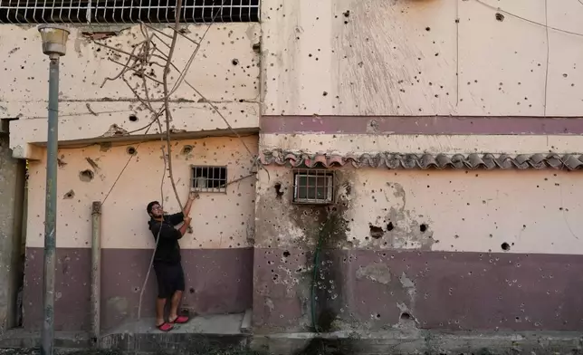 Dressle Perez removes twisted metal from a damaged apartment complex that residents say was hit during U.S. strikes to capture Venezuelan President Nicolás Maduro, in Catia La Mar, Venezuela, Sunday, Jan. 4, 2026.(AP Photo/Matias Delacroix)