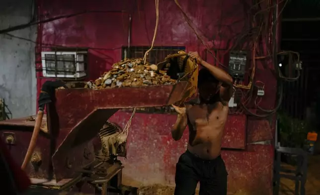 Marcovich Gonzalez loads rocks and soil into a machine that crushes it at a mill that processes material from nearby pits to extract gold in El Callao, Venezuela, Tuesday, Jan. 22, 2026. (AP Photo/Matias Delacroix)