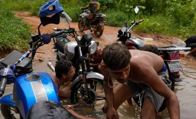 Gold miners wash their motorbike in a creek in El Callao, Venezuela, Tuesday, Jan. 22, 2026. (AP Photo/Matias Delacroix)