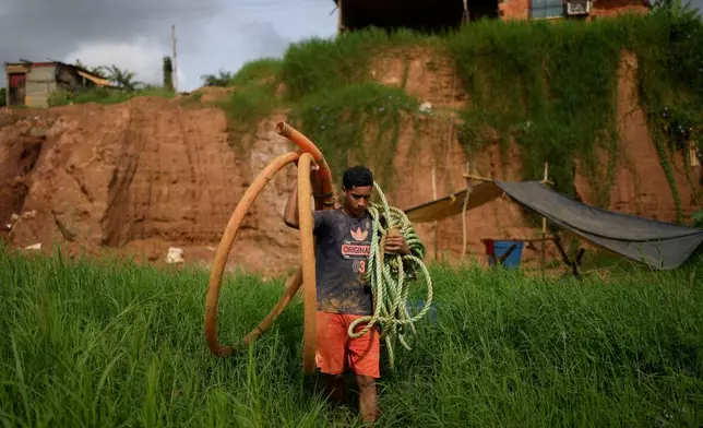 A miner carries a hose to a pit at a gold mine in El Callao, Venezuela, Tuesday, Jan. 22, 2026. (AP Photo/Matias Delacroix)