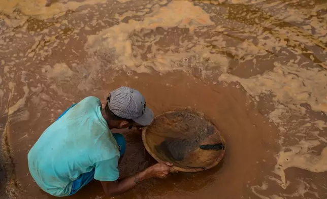 A man pans for gold in a pond next to a mill where rock and sediment are crushed and processed to extract gold in El Callao, Venezuela, Tuesday, Jan. 22, 2026. (AP Photo/Matias Delacroix)