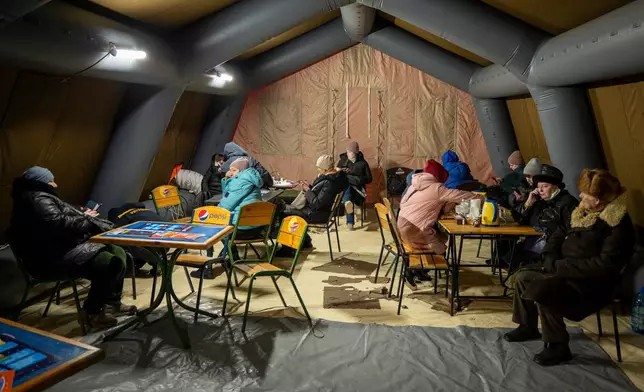 People get warm and charge their batteries in a tent set up by the emergency service following Russia's regular air attacks against the country's energy objects, in Kyiv, Ukraine, Tuesday, Jan. 13, 2026. (AP Photo/Danyil Bashakov)
