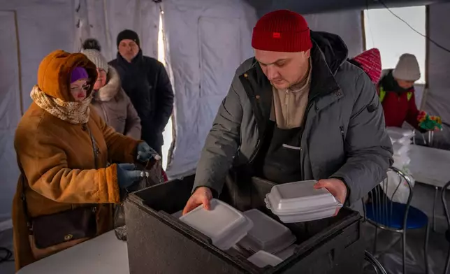 Residents get free food at an emergency center set up to support people during power outages caused by Russia's regular air attacks on the country's energy objects in Boryspil, Ukraine, Wednesday, Jan. 14, 2026. (AP Photo/Dan Bashakov)