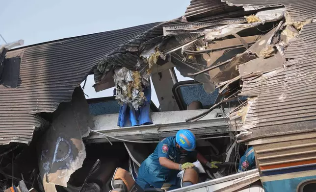 A rescuer searches amidst the wreckage after a construction crane fell into a passenger train in Nakhon Ratchasima province, Thailand, Wednesday, Jan.14, 2026. (AP Photo/Sakchai Lalit))