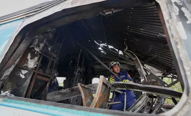 A rescuer works amidst the wreckage after a construction crane fell into a passenger train in Nakhon Ratchasima province, Thailand, Wednesday, Jan.14, 2026. (AP Photo/Sakchai Lalit))