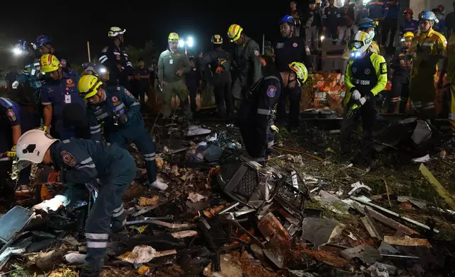 Rescuers inspects the wreckage after a construction crane fell onto a passenger train in Nakhon Ratchasima province, Thailand, Wednesday, Jan. 14, 2026. (AP Photo/Sakchai Lalit)