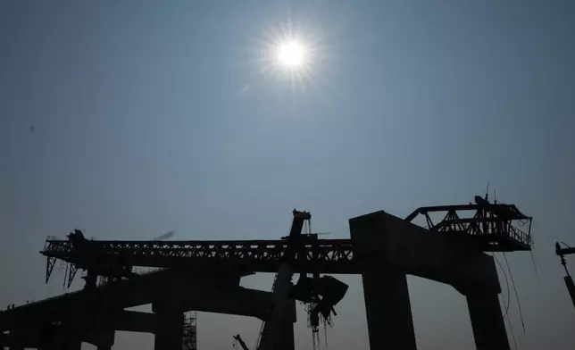 The construction site with crane wreckage is silhouetted, a day after the crane fell into a passenger train in Nakhon Ratchasima province, Thailand, Thursday, Jan. 15, 2026. (AP Photo/Sakchai Lalit)