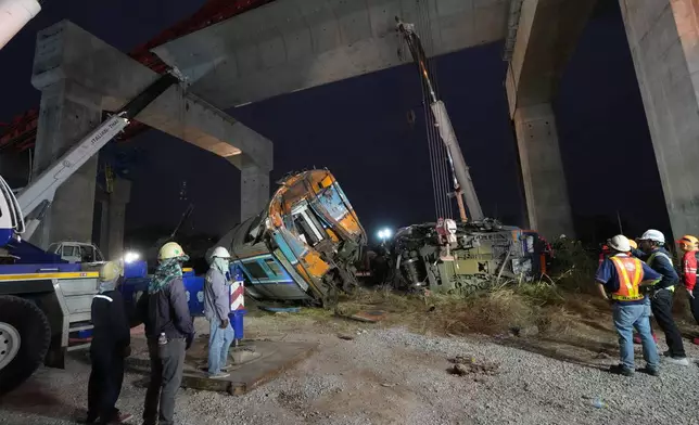 Rescuers try to lift the wreckage after a construction crane fell onto a passenger train in Nakhon Ratchasima province, Thailand, Wednesday, Jan. 14, 2026. (AP Photo/Sakchai Lalit)
