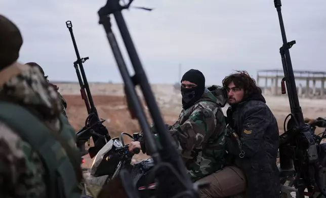 Syrian government soldiers carry machine guns as they ride motorcycles on a road leading to the town of Deir Hafer, Syria, Saturday, Jan. 17, 2026. (AP Photo/Ghaith Alsayed)