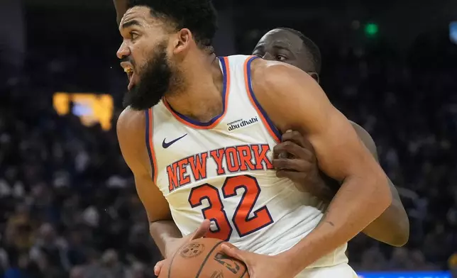 New York Knicks center Karl-Anthony Towns (32) is fouled by Golden State Warriors forward Draymond Green, rear, during the first half of an NBA basketball game in San Francisco, Thursday, Jan. 15, 2026. (AP Photo/Jeff Chiu)