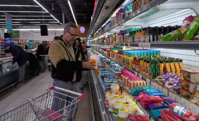 A man checks information on a yogurt's package at a store in Tehran, Iran, Friday, Jan. 16, 2026. (AP Photo/Vahid Salemi)