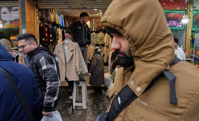 A shopkeeper holds garments at his store at Tehran's historic Grand Bazaar, Tuesday, Jan. 20, 2026, in Iran. (AP Photo/Vahid Salemi)