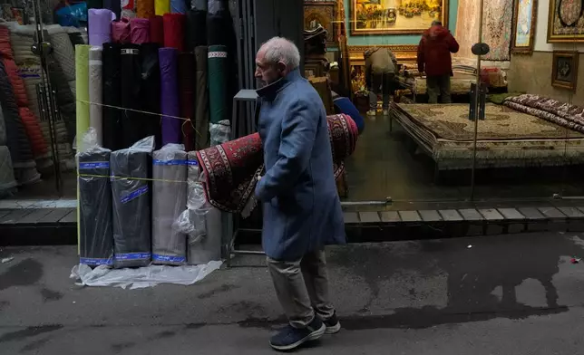 A man carries a carpet at Tehran's historic Grand Bazaar, Tuesday, Jan. 20, 2026, in Iran. (AP Photo/Vahid Salemi)