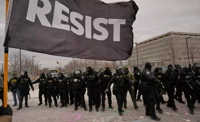 Federal immigration officers confront protesters outside Bishop Henry Whipple Federal Building, Thursday, Jan. 15, 2026, in Minneapolis. (AP Photo/John Locher)
