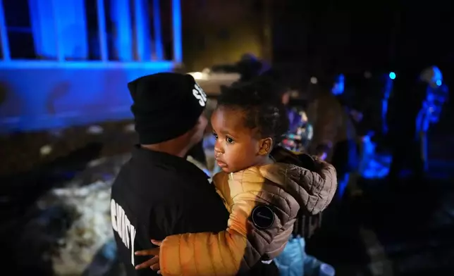 A child and family are escorted away after federal law enforcement deployed tear gas in a neighborhood during protests on Wednesday, Jan. 14, 2026, in Minneapolis. (AP Photo/Adam Gray)