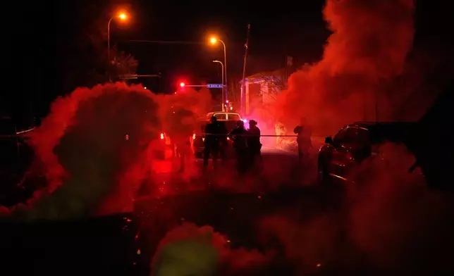 Tear gas surrounds federal law enforcement officers as they leave a scene after a shooting on Wednesday, Jan. 14, 2026, in Minneapolis. (AP Photo/John Locher)