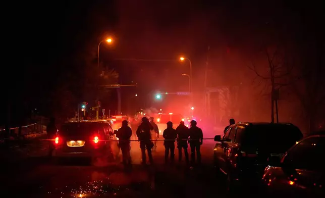 Tear gas surrounds federal law enforcement officers as they leave a scene after a shooting on Wednesday, Jan. 14, 2026, in Minneapolis. (AP Photo/John Locher)