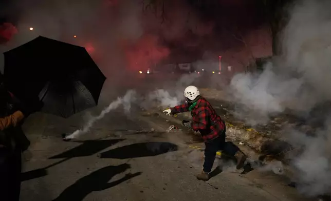 A protester throws back a tear gas canister during a protest after a shooting on Wednesday, Jan. 14, 2026, in Minneapolis. (AP Photo/John Locher)