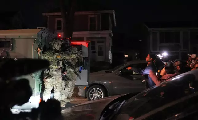 Protesters shout at law enforcement officers after a shooting on Wednesday, Jan. 14, 2026, in Minneapolis. (AP Photo/Abbie Parr)