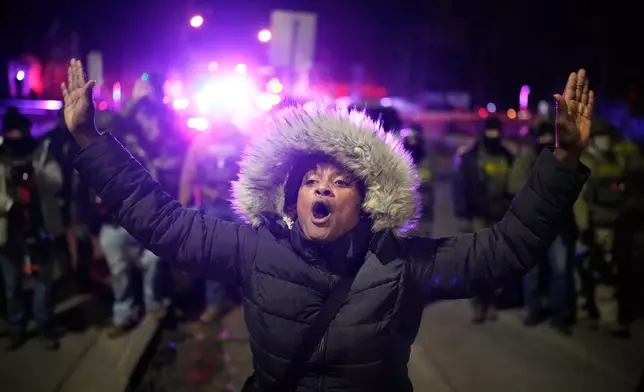 A protester yells in front of law enforcement after a shooting on Wednesday, Jan. 14, 2026, in Minneapolis. (AP Photo/John Locher)