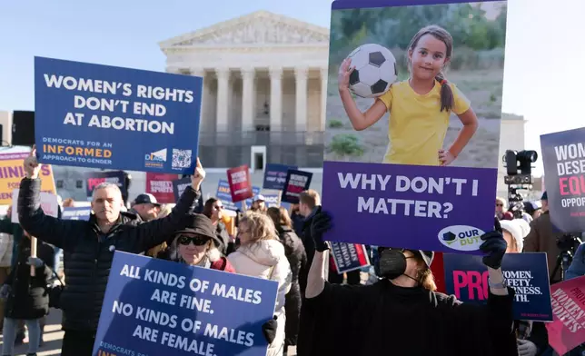 Protesters gather outside the Supreme Court as it hears arguments over state laws barring transgender girls and women from playing on school athletic teams, Tuesday, Jan. 13, 2026, in Washington. (AP Photo/Jose Luis Magana)