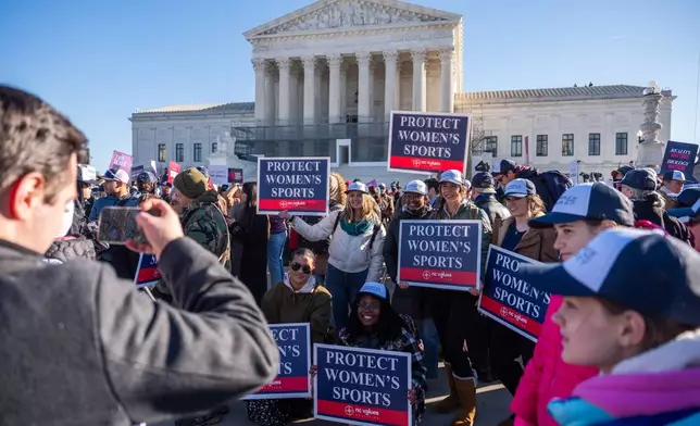 Protesters gather outside the Supreme Court as it hears arguments over state laws barring transgender girls and women from playing on school athletic teams, Tuesday, Jan. 13, 2026, in Washington. (AP Photo/Julia Demaree Nikhinson)
