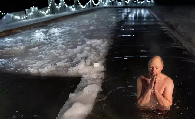 A Lithuanian Orthodox believer bathes in the icy water shortly after midnight during a traditional Epiphany celebration in a lake near Vilnius, Lithuania, Monday, Jan. 19, 2026, with air temperatures at -17 degrees Celsius (1.4 degrees Fahrenheit) and water temperatures at 0.4 degrees Celsius (32.7 degrees Fahrenheit). (AP Photo/Mindaugas Kulbis)