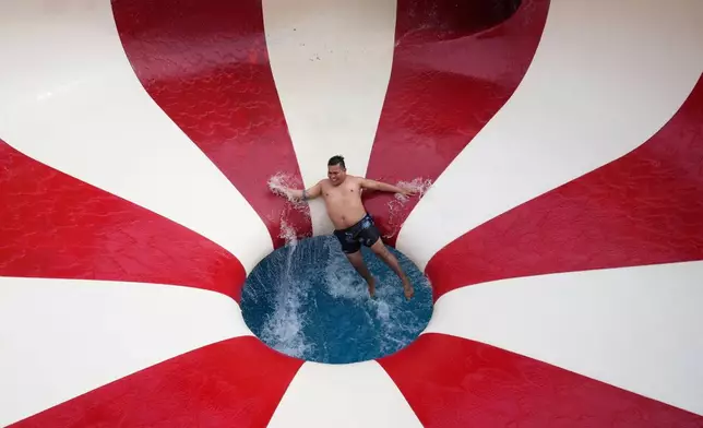 A man tumbles down a water slide in a public pool in the Puente Piedra district outside of Lima, Peru, Sunday, Jan. 18, 2026. (AP Photo/Martin Mejia)