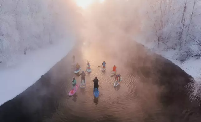 Standup paddleboarders sail along one of the branches of the Ob River that doesn't freeze even in such extreme cold as the temperature drops to −40°Celsius (-40 Fahrenheit) in Novosibirsk, Russia, Saturday, Jan. 17, 2026. (AP Photo/Vadim Makhorov)