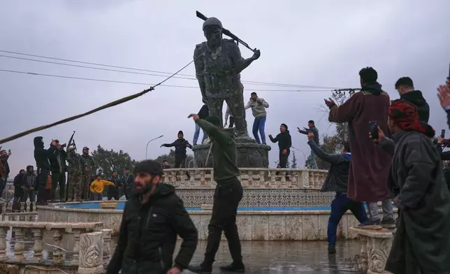 Residents topple a statue of a female Kurdish fighter after the takeover of the town by Syrian government forces from U.S.-backed Syrian Democratic Forces (SDF), in Tabqa, eastern Syria, Sunday, Jan. 18, 2026. (AP Photo/Ghaith Alsayed)