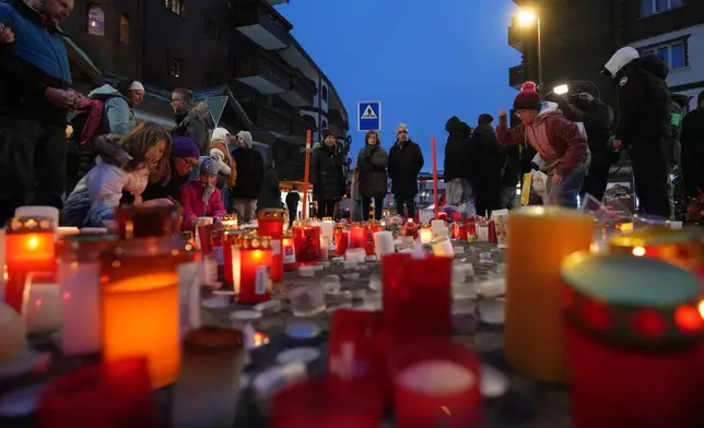 People light candles near the sealed off Le Constellation bar in Crans-Montana, Swiss Alps, Switzerland, Friday, Jan. 2, 2026, where a devastating fire left dead and injured during the New Year's celebrations. (AP Photo/ Antonio Calanni)