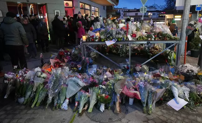 People lay flowers near the sealed off Le Constellation bar in Crans-Montana, Swiss Alps, Switzerland, Friday, Jan. 2, 2026, where a devastating fire left dead and injured during the New Year's celebrations. (AP Photo/ Antonio Calanni)