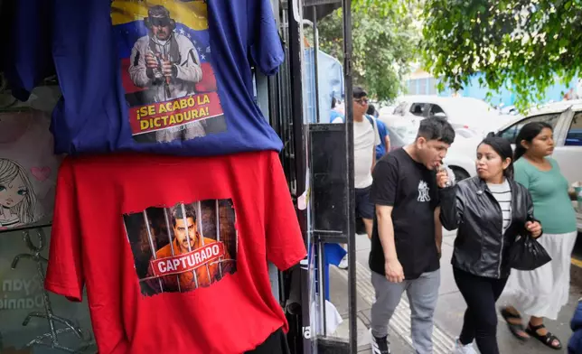Pedestrians pass T-shirts featuring images of Venezuelan President Nicolas Maduro at at a printing shop in Lima, Peru, Monday, Jan. 5, 2026, two days after U.S. forces captured and removed him from Venezuela. (AP Photo/Martin Mejia)