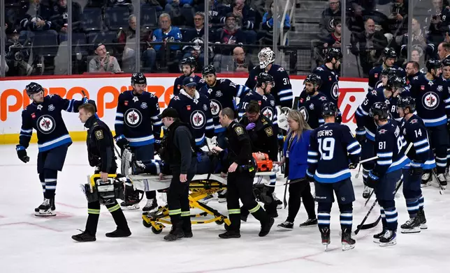 Winnipeg Jets' Haydn Fleury is helped off the ice after being injured against the Vegas Golden Knights during the first period of their NHL hockey game in Winnipeg, Tuesday Jan. 6, 2026. (Fred Greenslade/The Canadian Press via AP)