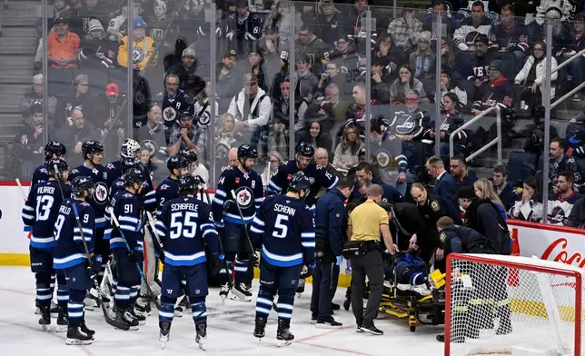 Winnipeg Jets' Haydn Fleury is helped off the ice after being injured against the Vegas Golden Knights during the first period of their NHL hockey game in Winnipeg, Tuesday Jan. 6, 2026. (Fred Greenslade/The Canadian Press via AP)
