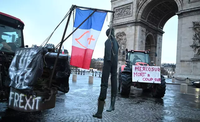A mannequin hangs from a tractor as farmers protest at the Arc de Triomphe against the Mercosur trade alliance with South America countries but also against EU farming policy or mass cull of cows ordered to contain the spread of a skin disease, Thursday, Jan. 8, 2026 in Paris. Poster at right reads: Mercosur, death for sure. (AP Photo/Emma Da Silva)